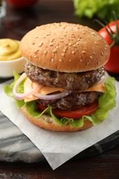 Photo of Tasty hamburger with patties, cheese and vegetables on wooden table
