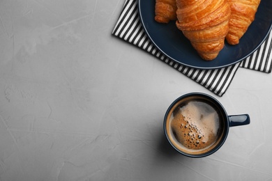 Flat lay composition with coffee and croissants on grey table, space for text