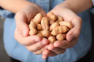 Woman holding raw peanuts in hands, closeup