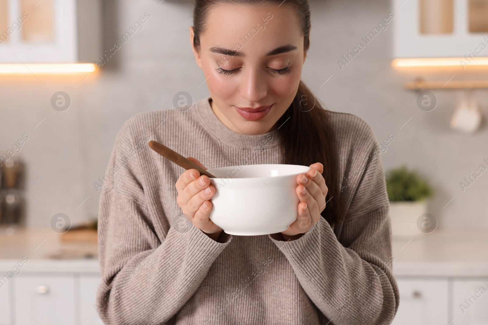 Photo of Woman with bowl of tasty soup in kitchen