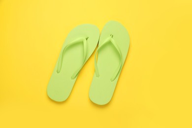 Photo of Stylish light green flip flops on yellow background, top view