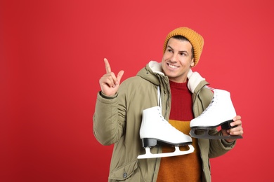 Happy man with ice skates on red background. Space for text