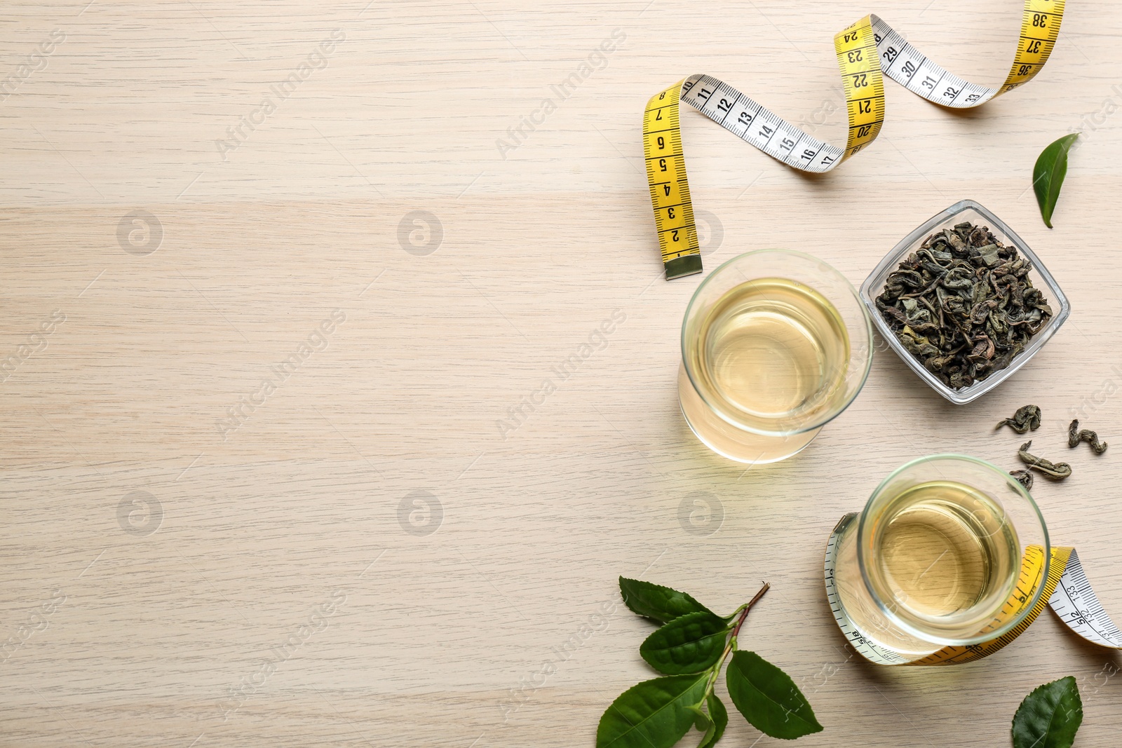 Photo of Flat lay composition with diet herbal tea and measuring tape on wooden background, space for text