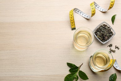 Photo of Flat lay composition with diet herbal tea and measuring tape on wooden background, space for text