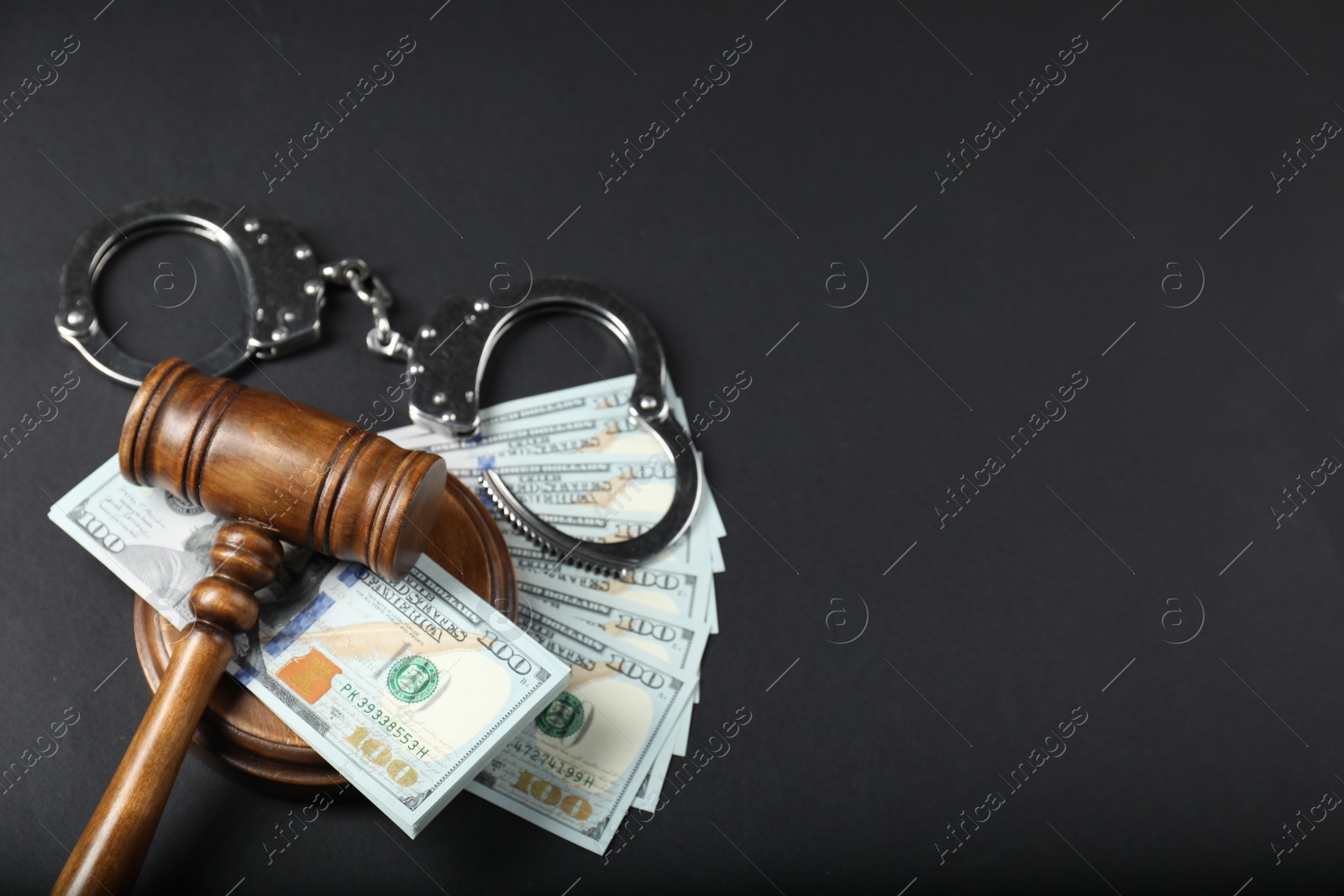 Photo of Law gavel, dollars and handcuffs on grey table, above view. Space for text