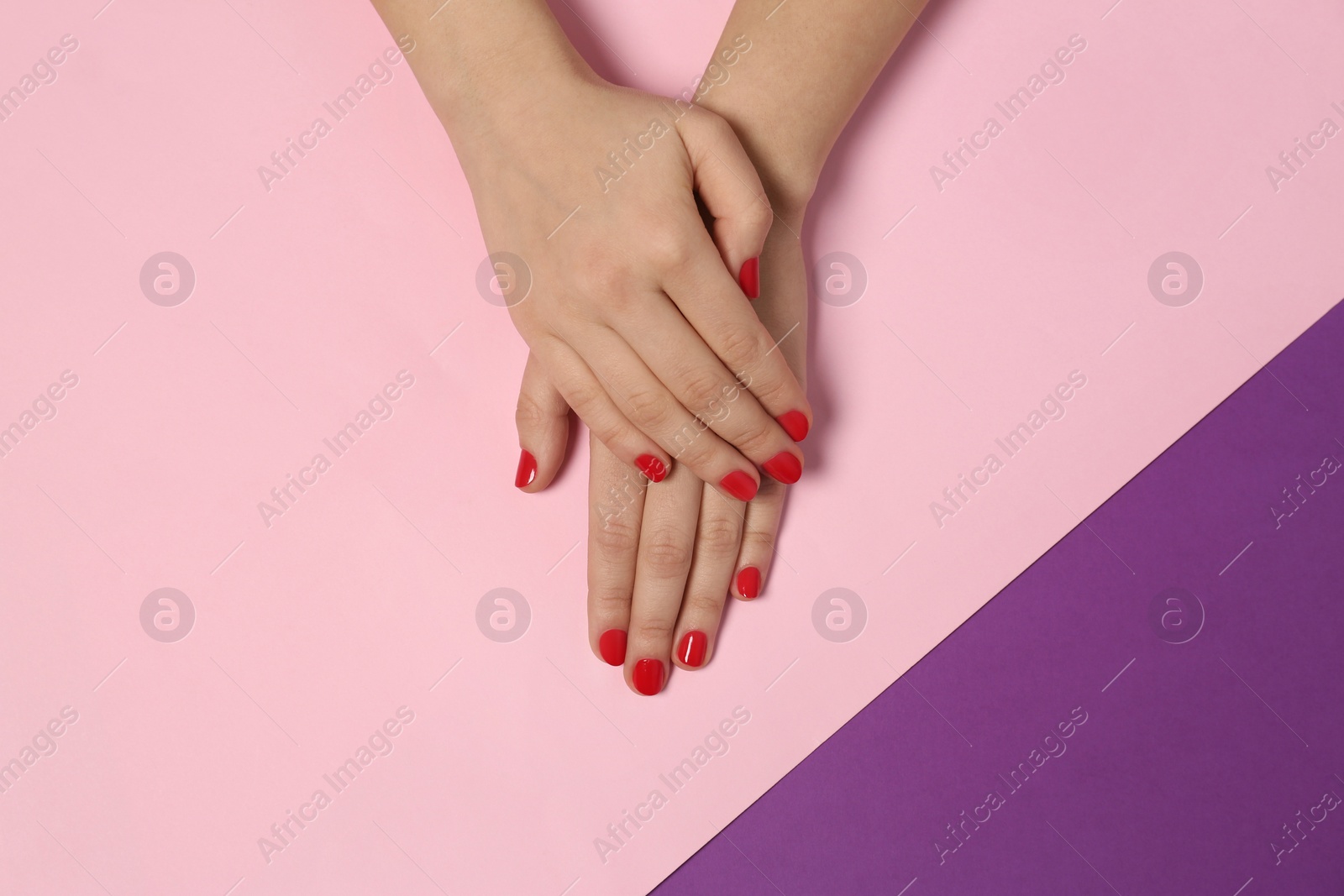 Photo of Woman showing red manicure on color background, top view. Nail polish trends