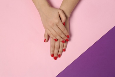 Woman showing red manicure on color background, top view. Nail polish trends