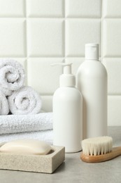 Photo of Different bath accessories and personal care products on gray table near white tiled wall