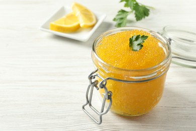 Photo of Fresh pike caviar in glass jar and parsley on light wooden table, closeup. Space for text