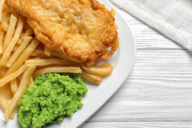 Photo of Plate with British traditional fish and potato chips on wooden background, closeup