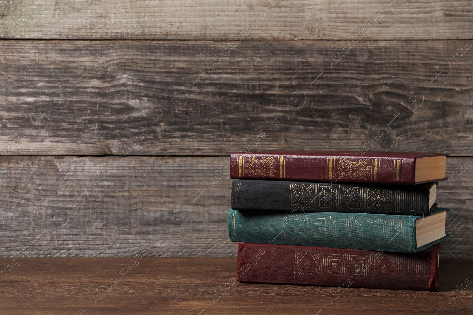 Photo of Stack of old hardcover books on wooden table, space for text