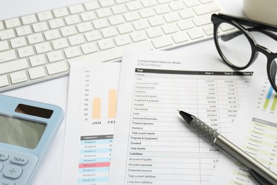 Accounting documents, stationery, glasses and computer keyboard on white table, closeup