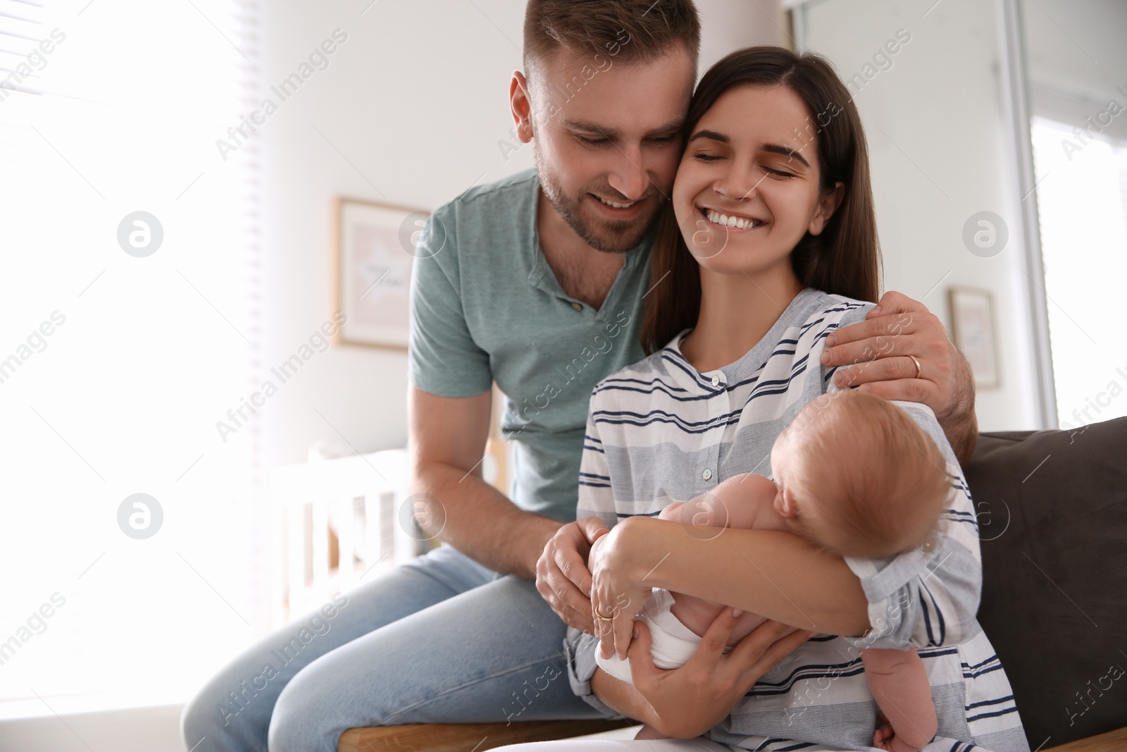 Photo of Happy couple with their newborn baby at home