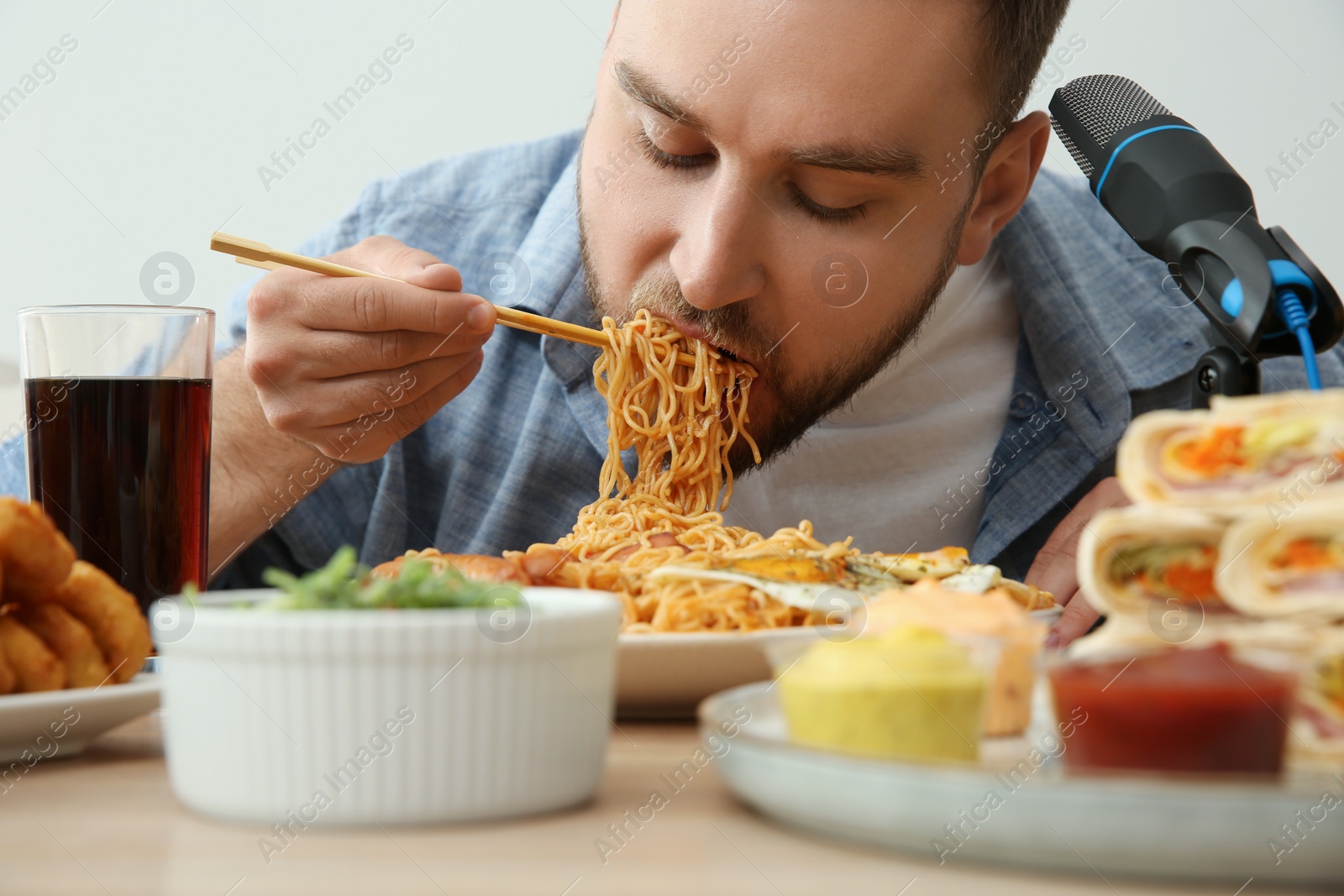 Photo of Food blogger eating in front of microphone at table, closeup. Mukbang vlog