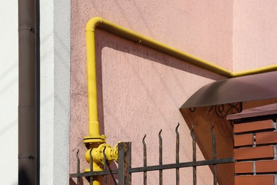 Photo of Yellow gas pipe on pink wall outdoors