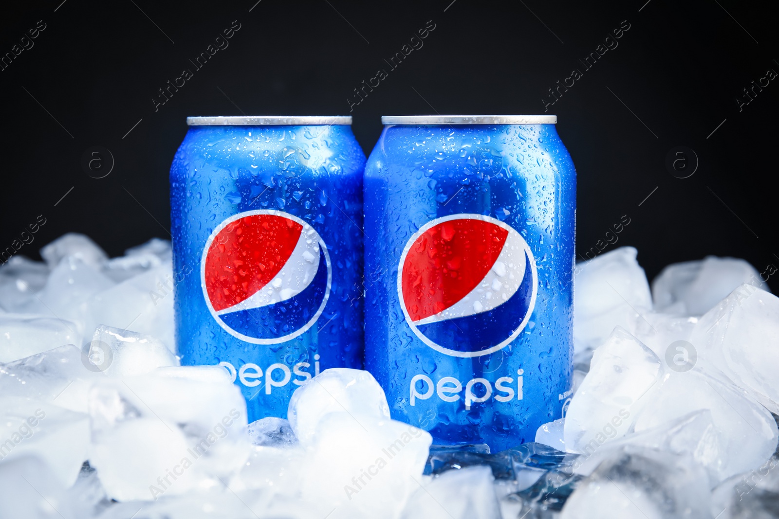 Photo of MYKOLAIV, UKRAINE - FEBRUARY 11, 2021: Cans of Pepsi on ice cubes against black background