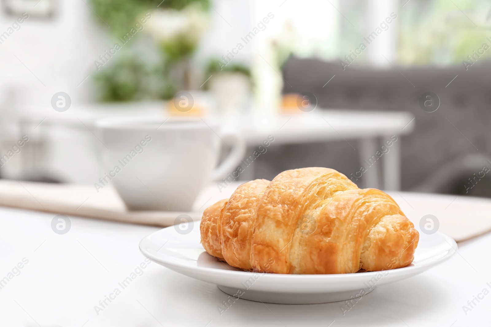 Photo of Plate with tasty freshly baked croissant on table