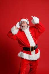 Merry Christmas. Santa Claus in headphones listening to music and singing on red background