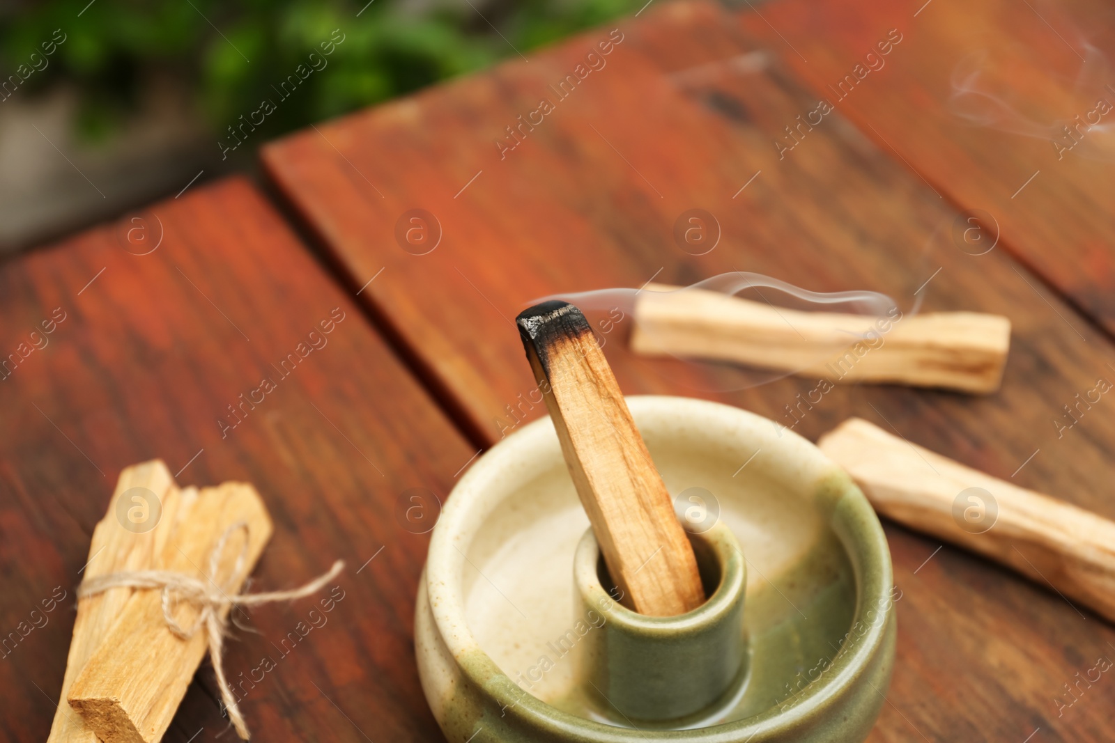 Photo of Palo Santo stick smoldering in holder on wooden table