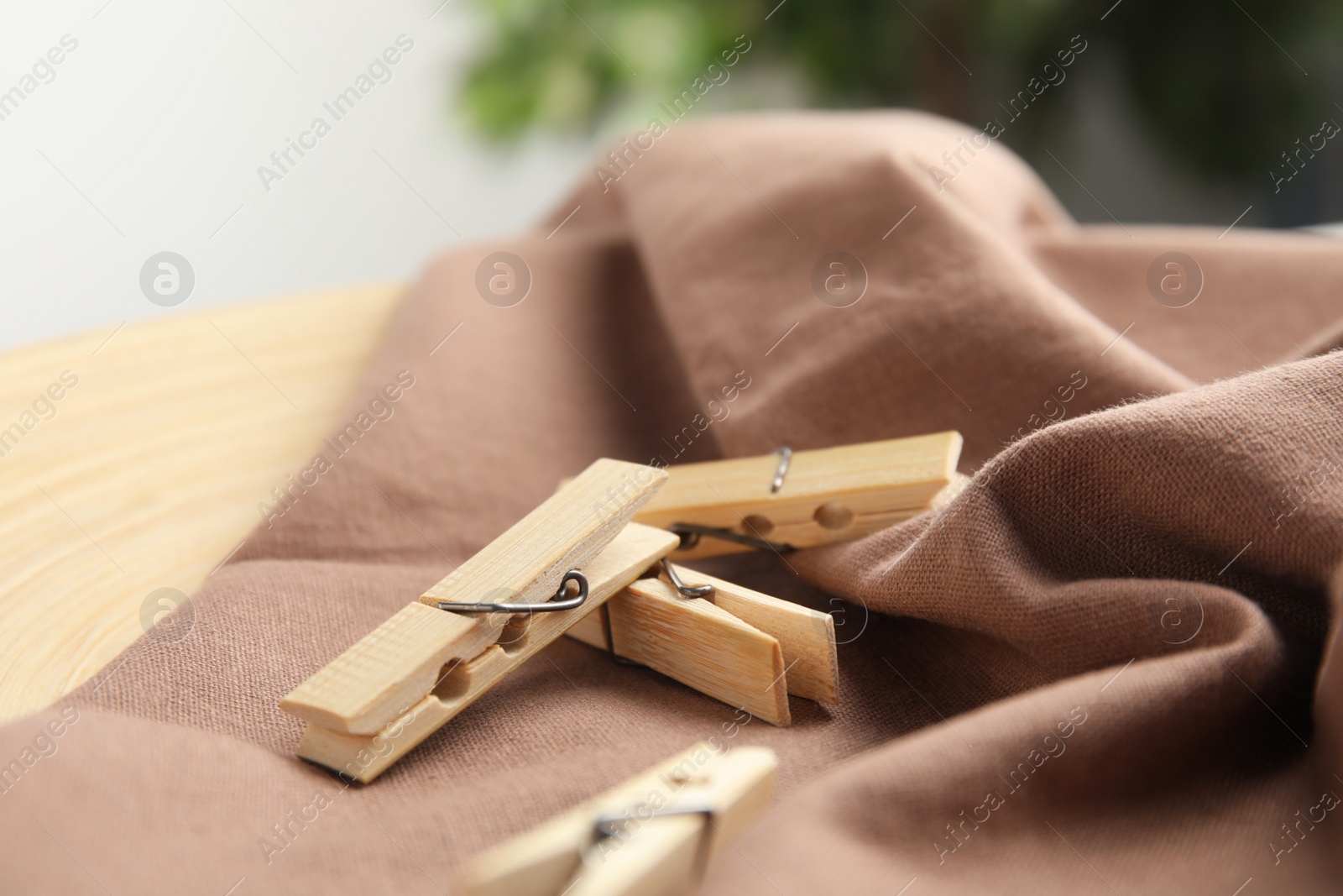 Photo of Many wooden clothespins on brown fabric, closeup