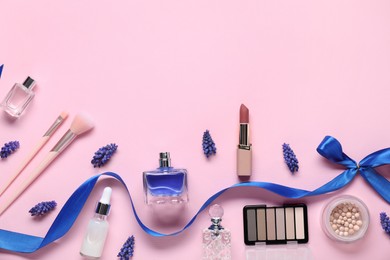 Photo of Flat lay composition with different makeup products and beautiful spring flowers on pink background. Space for text