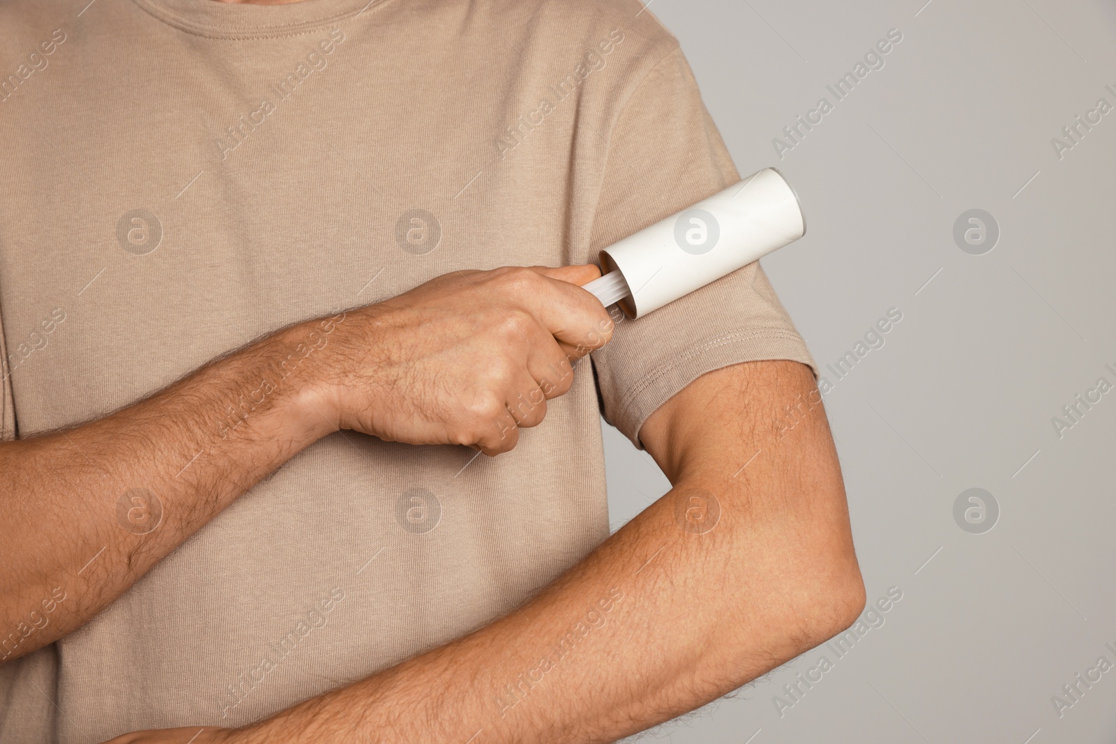 Photo of Man using lint roller on light grey background, closeup