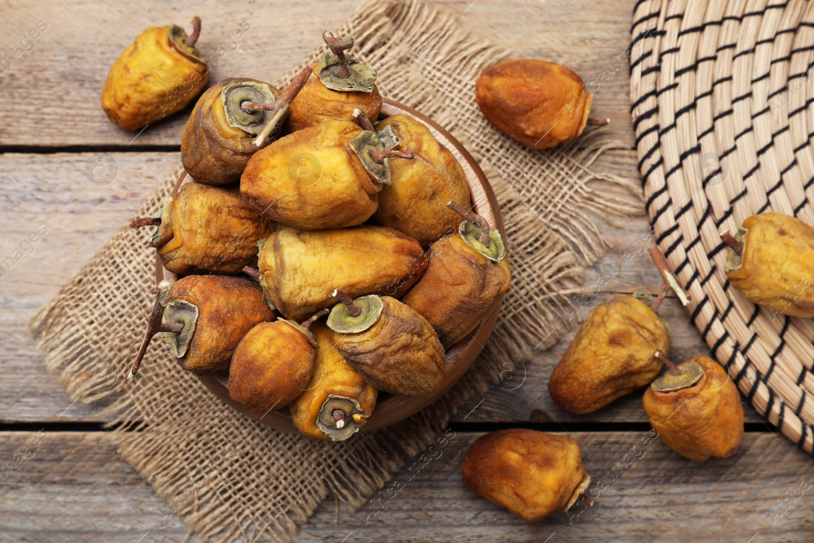 Photo of Bowl with tasty dried persimmon fruits on wooden table, flat lay