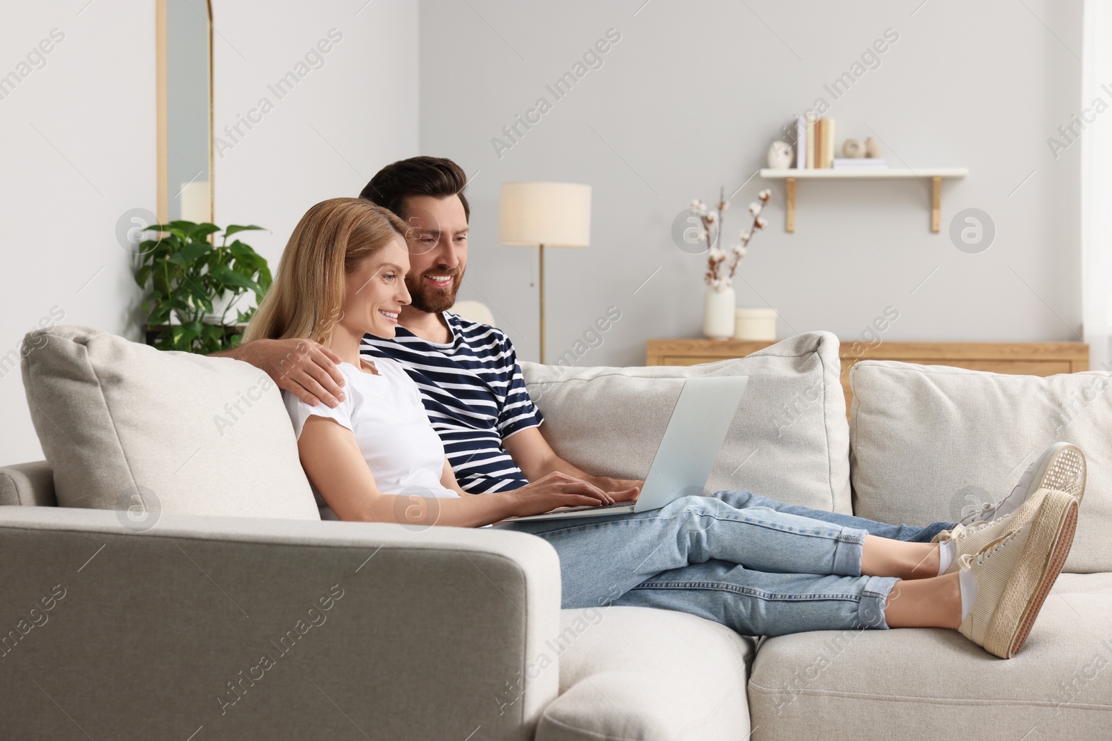 Photo of Happy couple with laptop on sofa at home