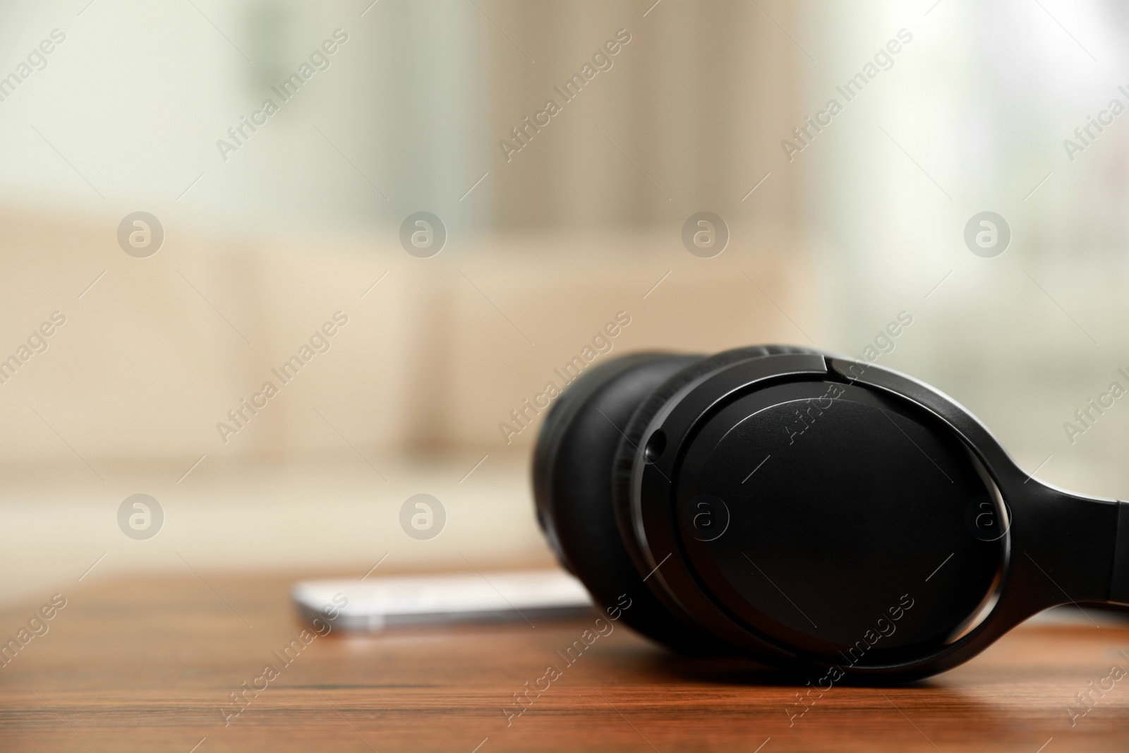 Photo of Modern wireless headphones on wooden table indoors, closeup. Space for text