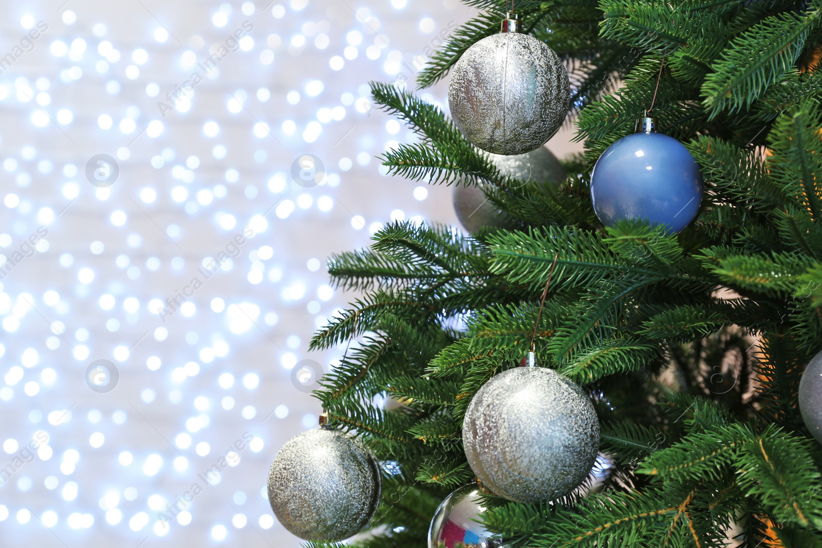 Photo of Christmas tree with festive decor against blurred fairy lights