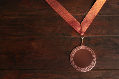 Photo of Bronze medal on wooden background, top view. Space for design