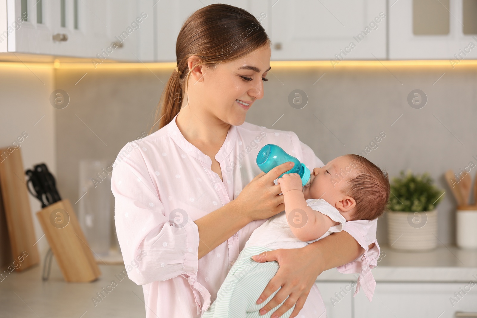 Photo of Mother feeding her cute child with infant formula indoors