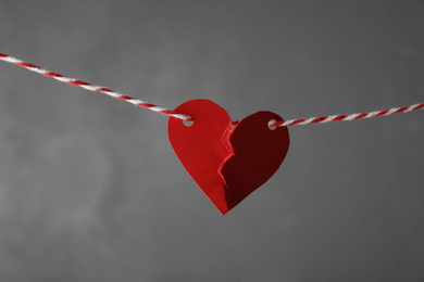 Broken red paper heart on rope against grey background. Relationship problems concept
