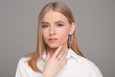 Photo of Beautiful young woman with elegant jewelry on gray background