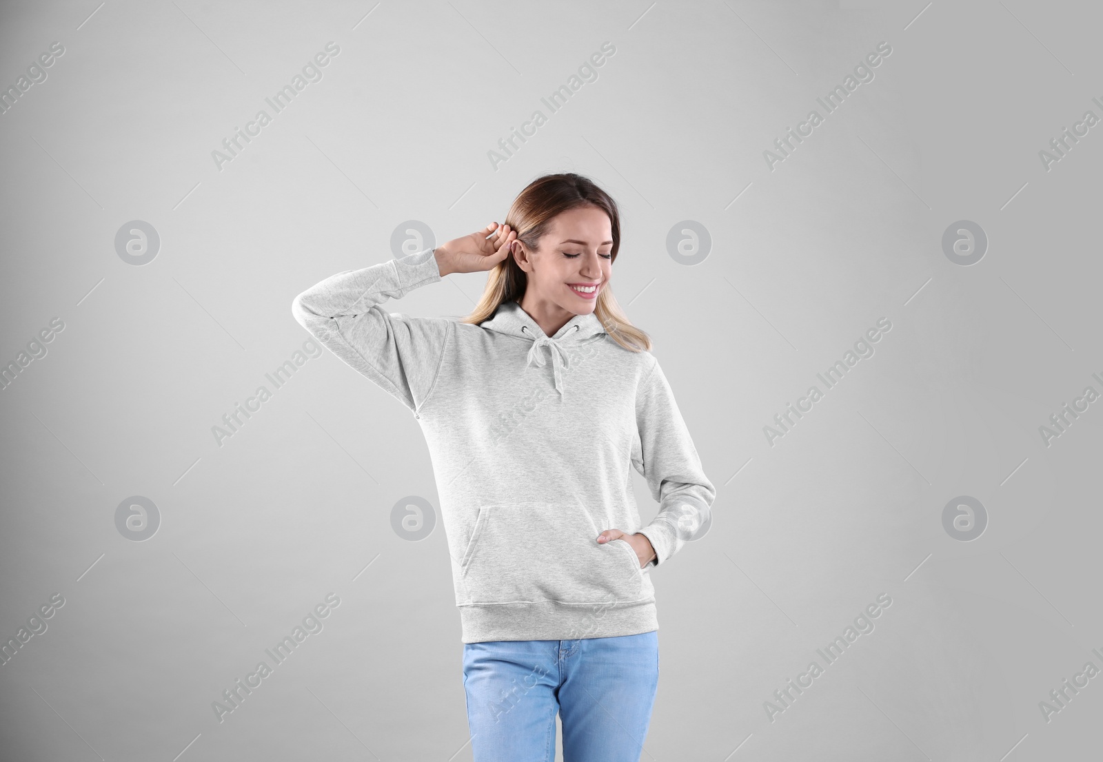 Photo of Portrait of woman in hoodie sweater on light background. Space for design