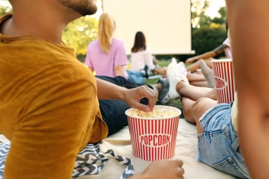 Young people with popcorn watching movie in open air cinema, closeup