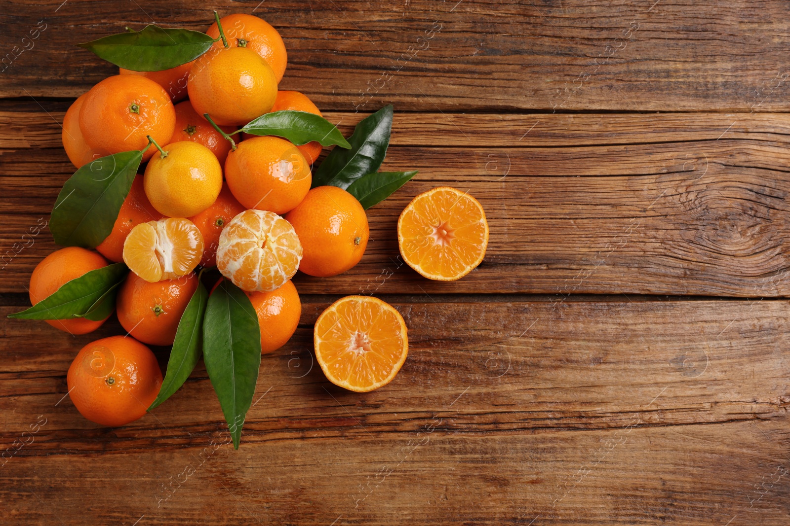 Photo of Fresh tangerines with green leaves on wooden table, top view. Space for text