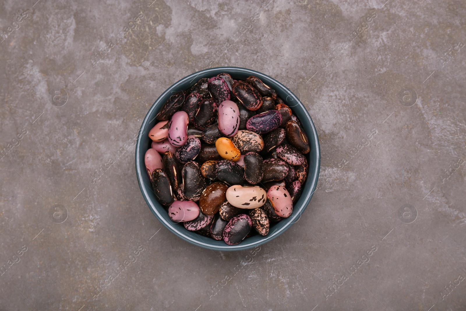 Photo of Bowl with dry kidney beans on grey table, top view