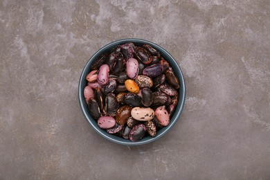 Photo of Bowl with dry kidney beans on grey table, top view