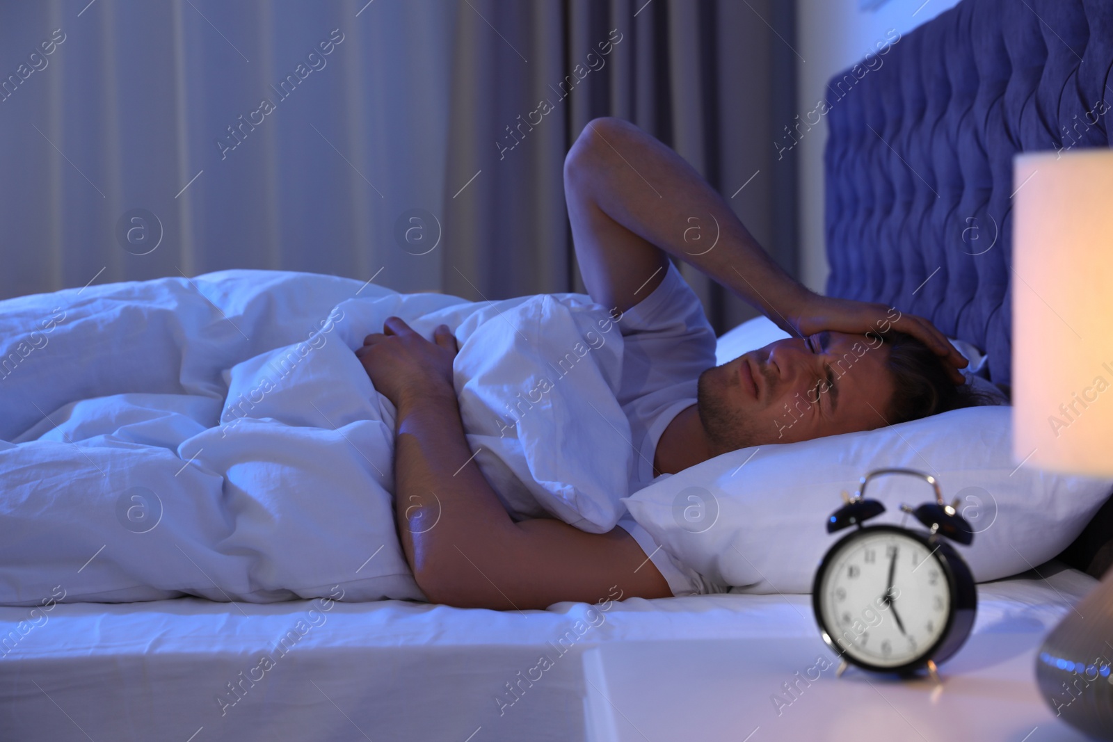 Photo of Sleepy young man lying on pillow at night. Bedtime