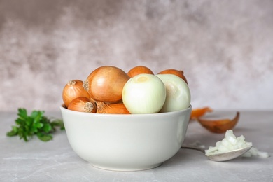 Photo of Bowl with fresh ripe onions on table