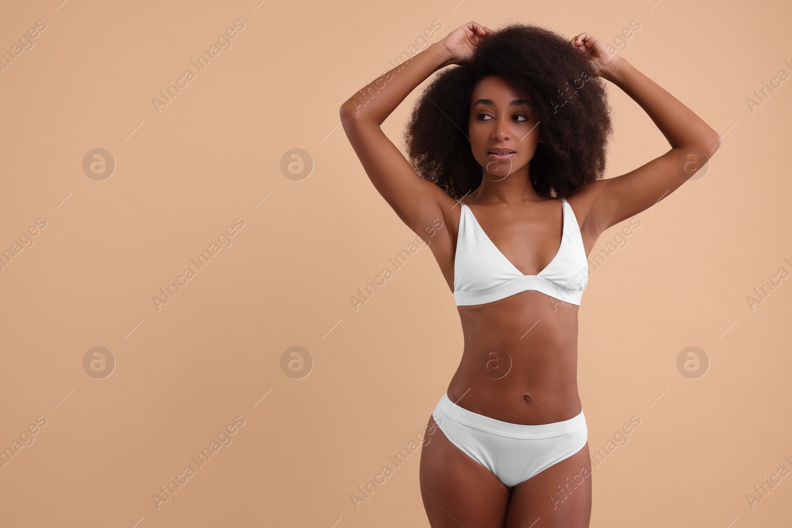 Photo of Beautiful woman in stylish bikini on beige background, space for text