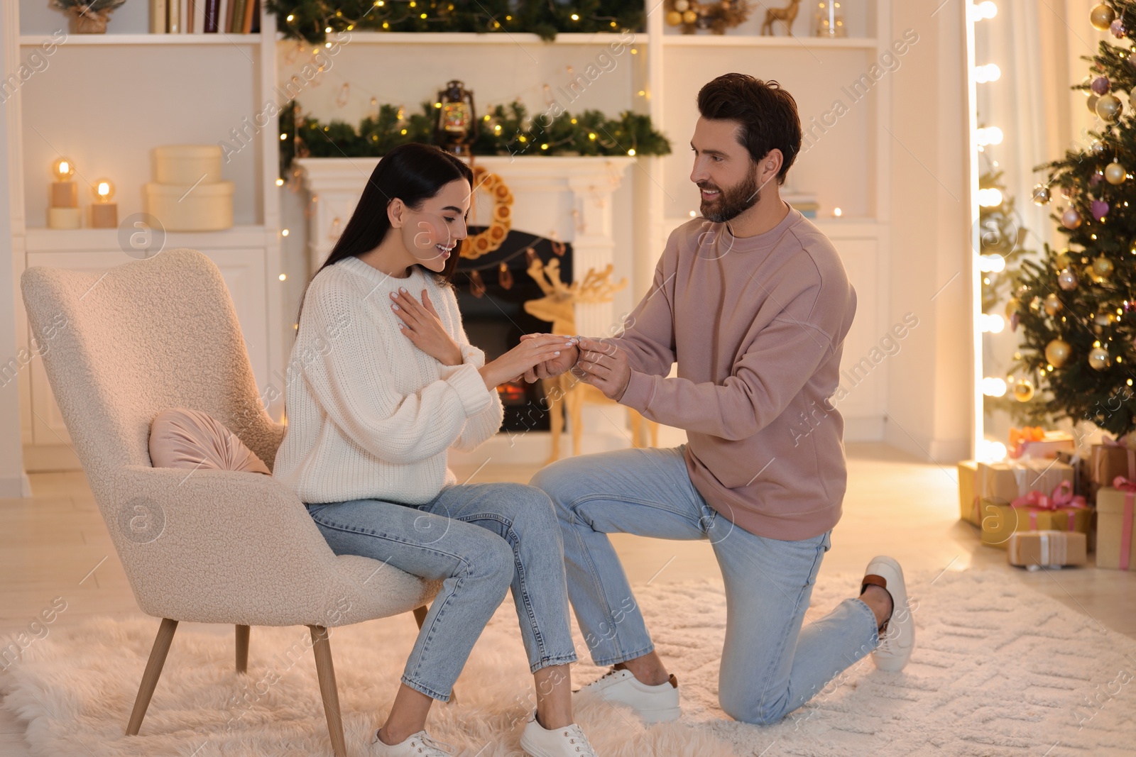 Photo of Making proposal. Man putting engagement ring on his girlfriend's finger at home on Christmas