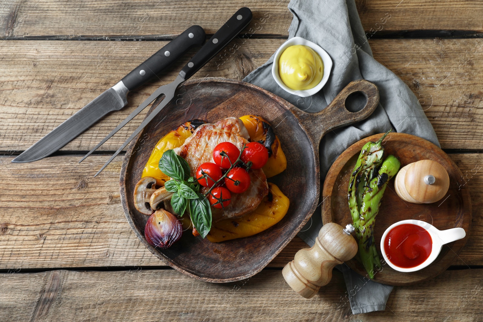 Photo of Delicious grilled meat and vegetables served with sauces on wooden table, flat lay