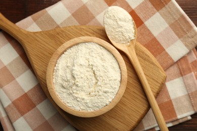 Baking powder in bowl and spoon on wooden table, top view