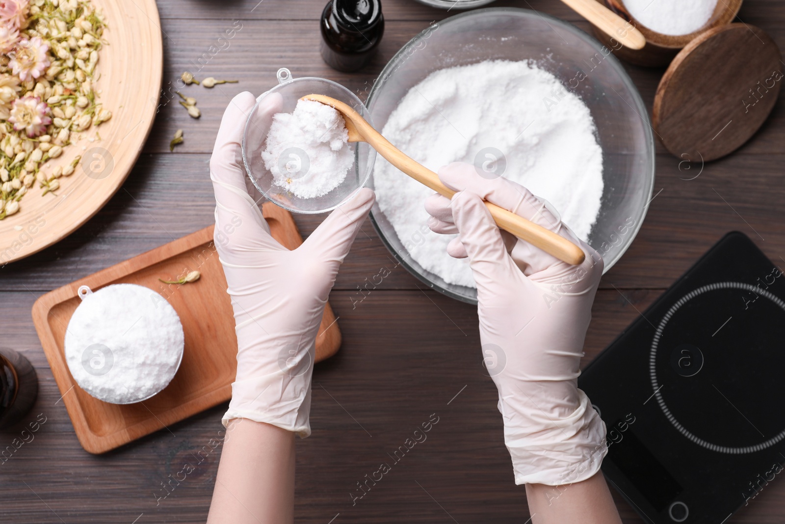 Photo of Woman in gloves making bath bomb at wooden table, top view