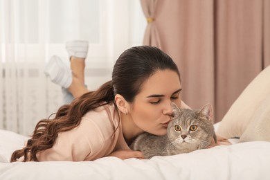 Young woman kissing her adorable cat at home