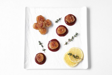 Photo of Delicious fried scallops with tomato sauce, thyme and lemon isolated on white, top view