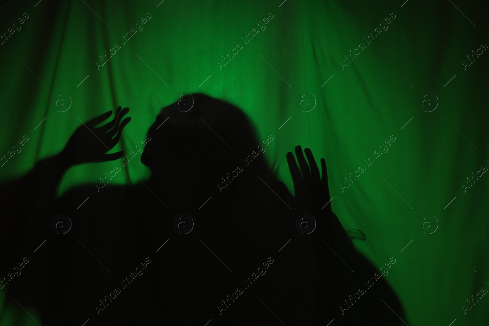 Photo of Silhouette of creepy ghost behind dark green cloth