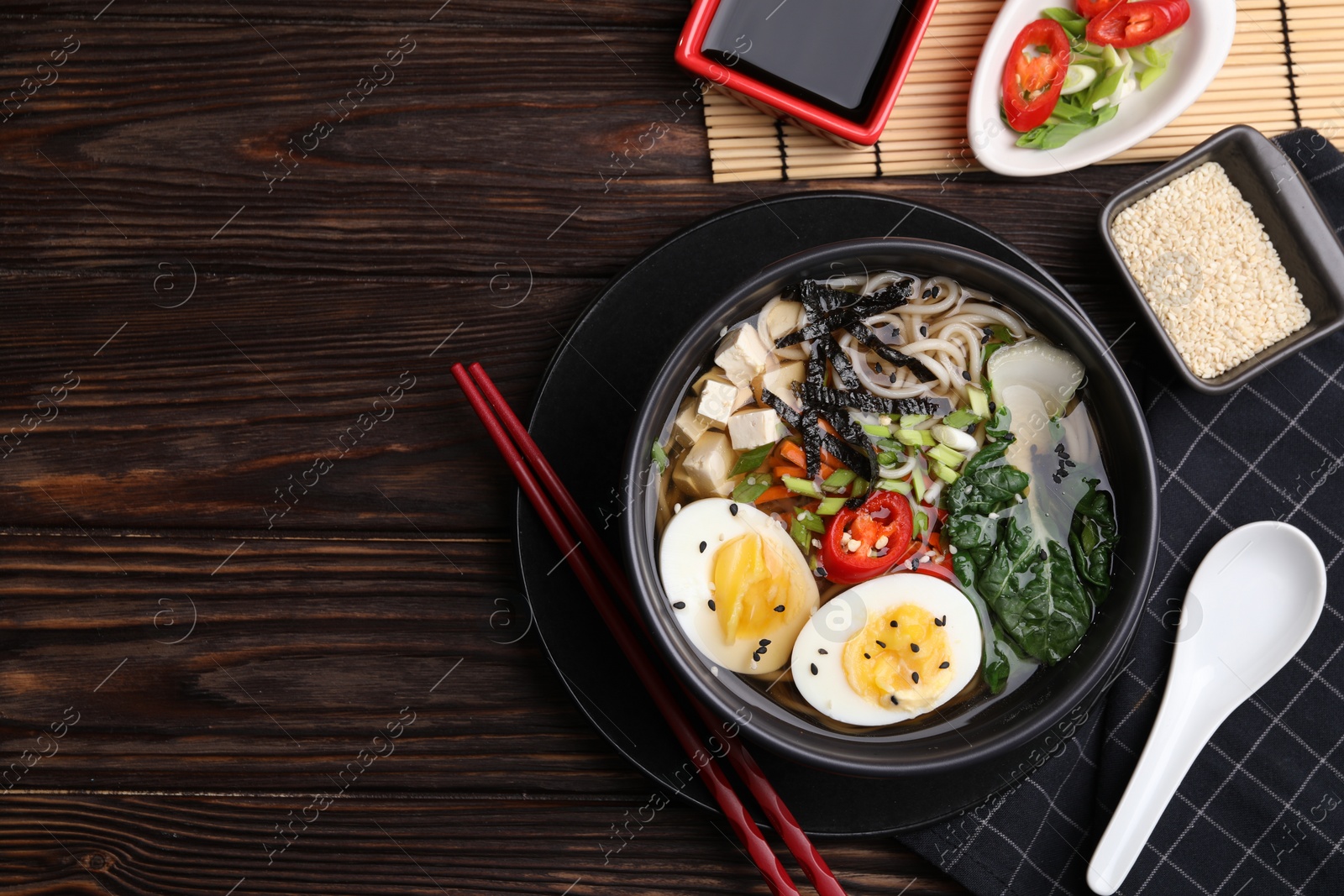 Photo of Delicious vegetarian ramen served on wooden table, flat lay with space for text. Noodle soup